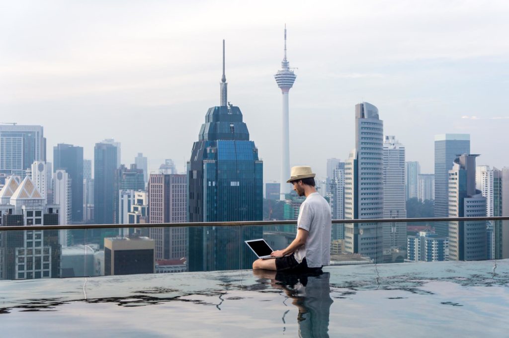 digital nomad in a pool on top of a building to make money while traveling