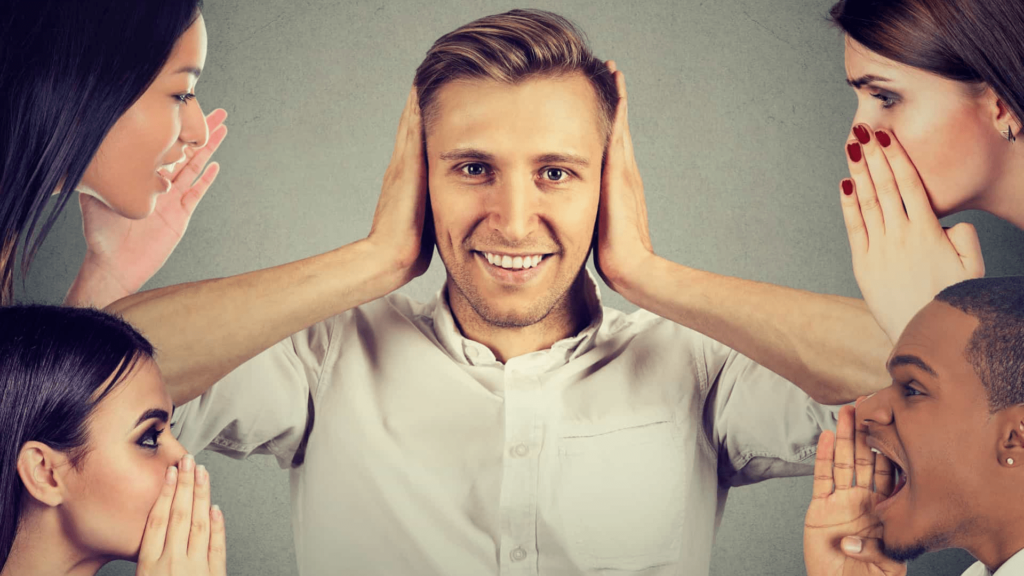 man covering his ears to the people around him