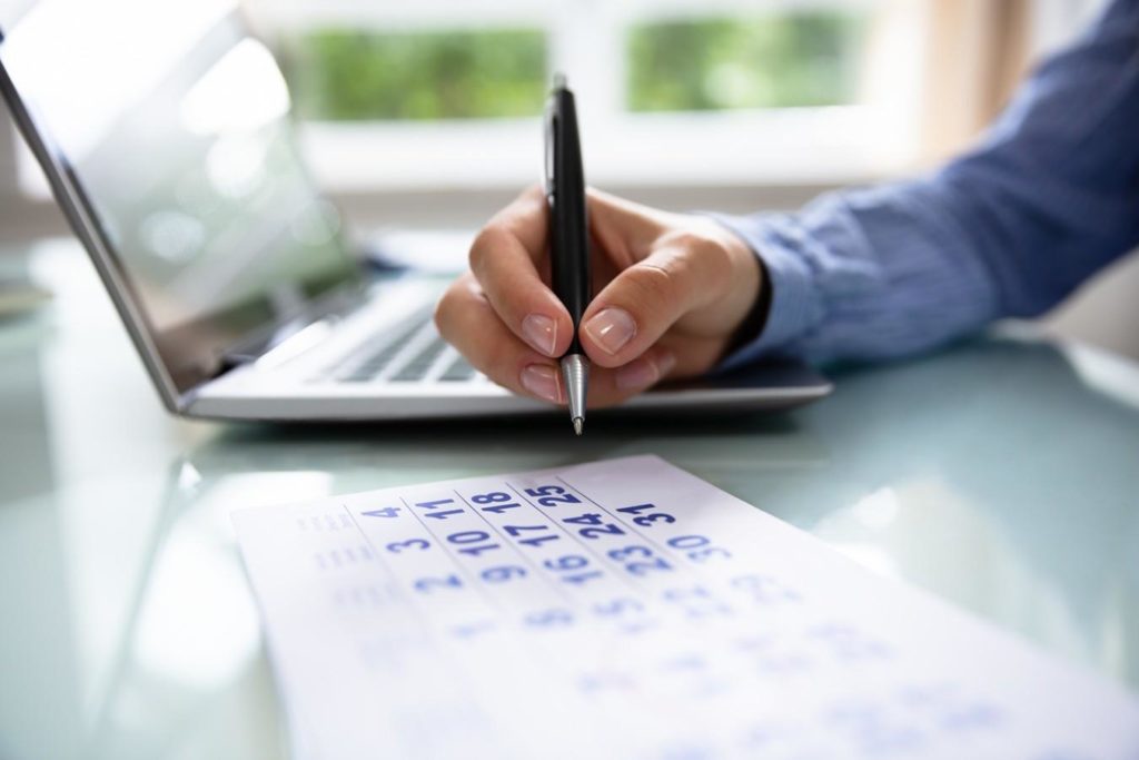 man writing to a calender